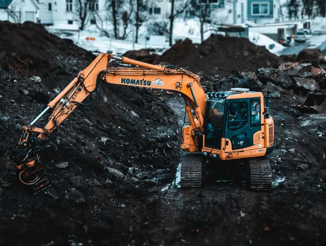 A heavy equipment operator using his excavator to dig deep holes for an underground pipe network.