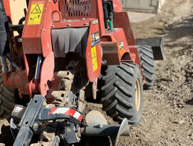 A small skidsteer with a grading attachment gets to work on a lot of gravel that needs leveled out.