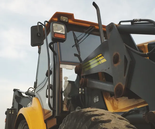 A close up shot of a tractor reveals its intricate details. The dents and scratches tell tales of the places it's been and the hard work it's done.