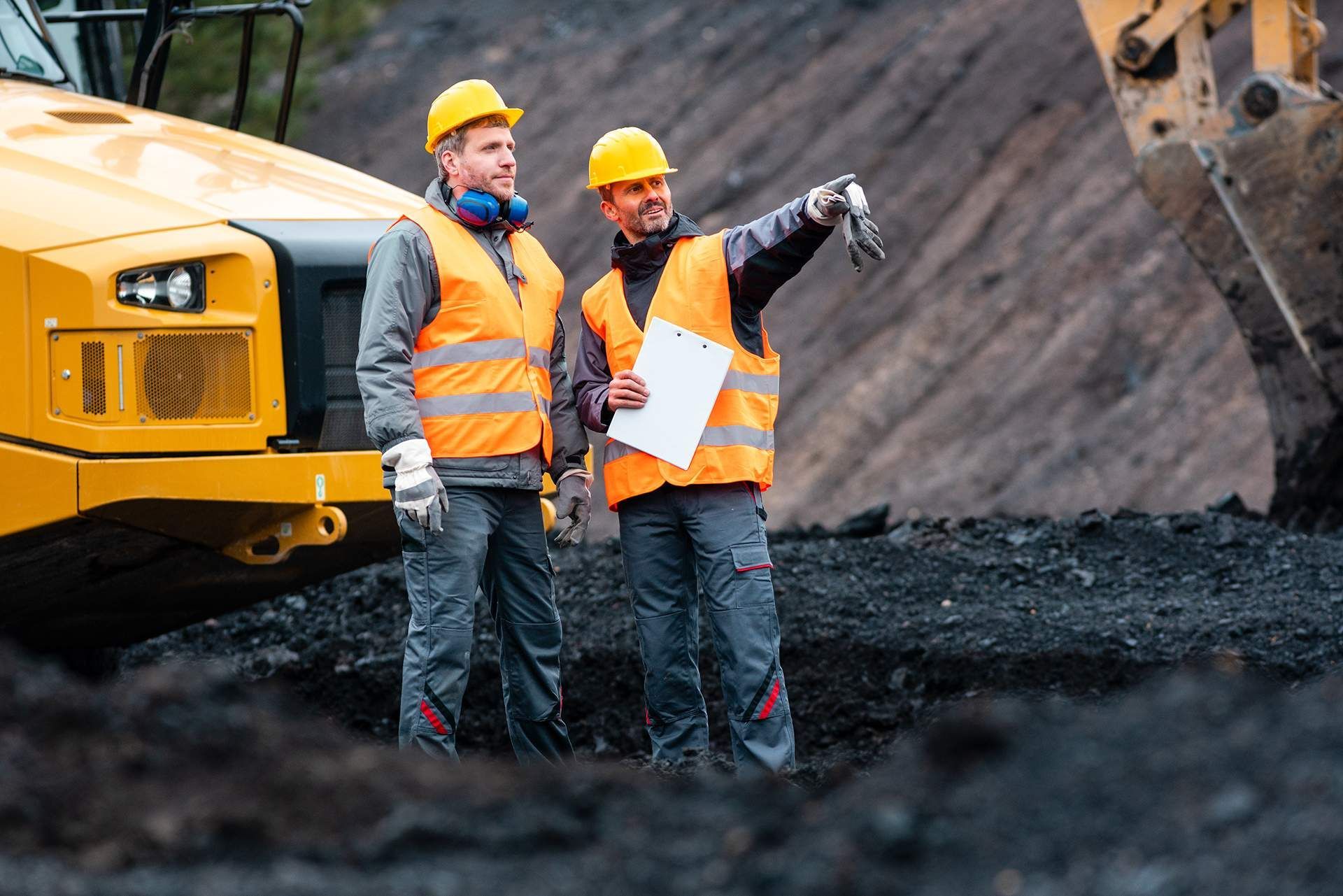 two construction workers standing in front of a yellow vehicle