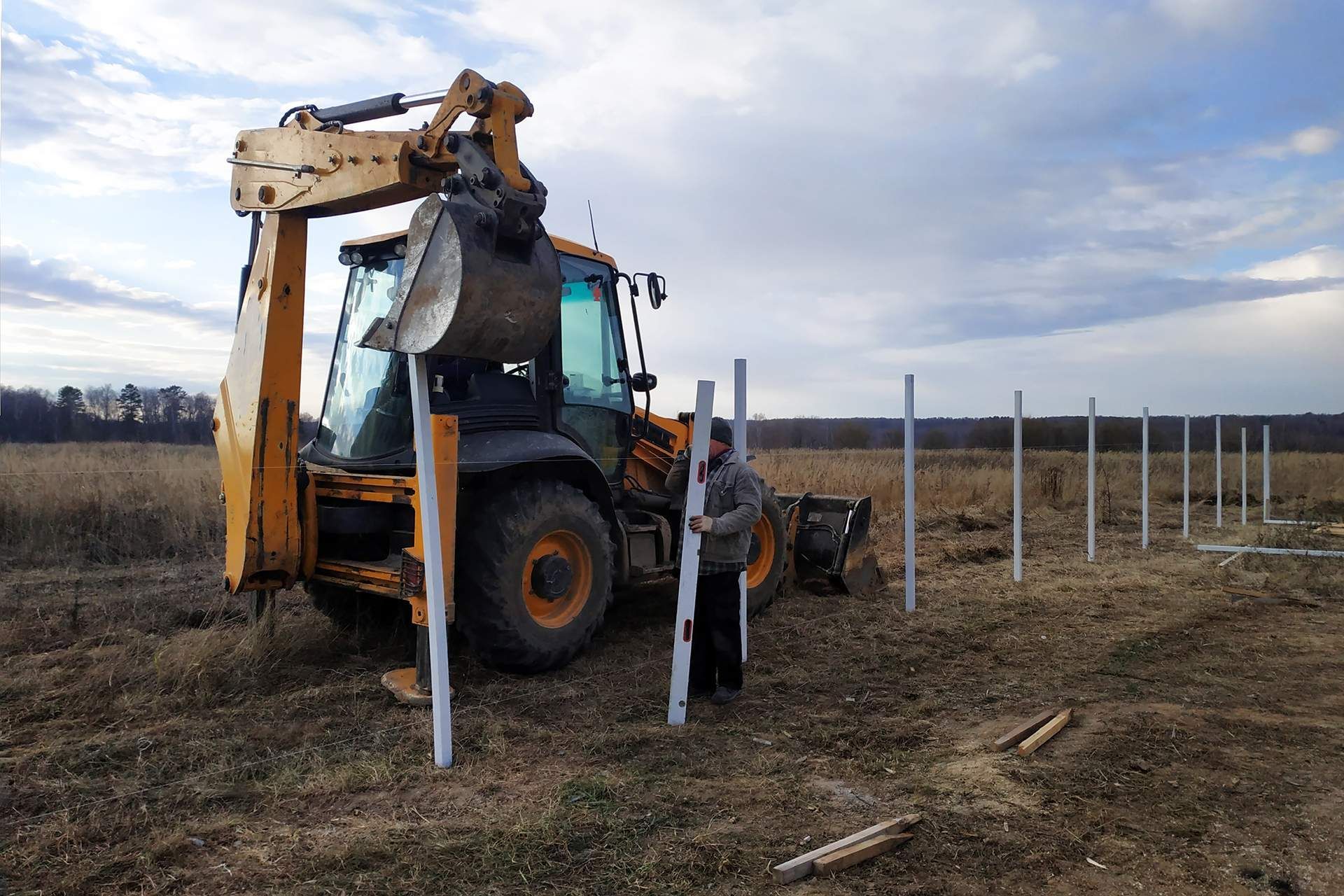 a man stands in front of a yellow and black tractor