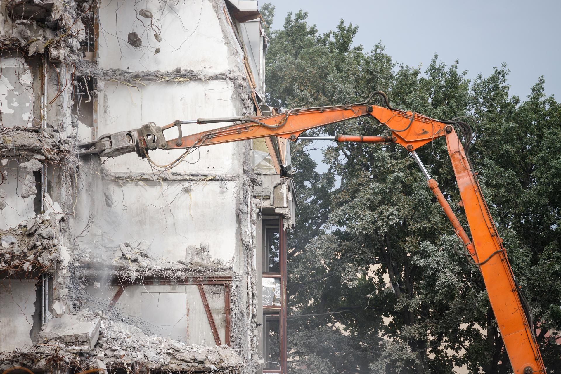 a large orange excavator is demolishing a building