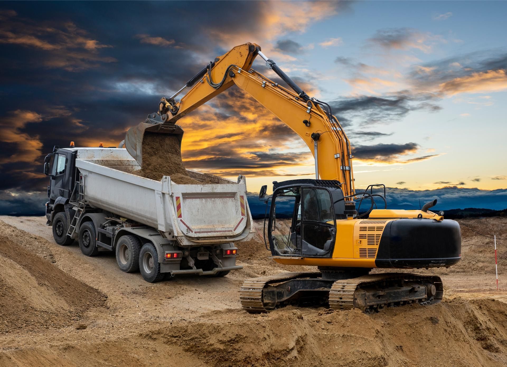 an excavator is loading dirt into a dump truck