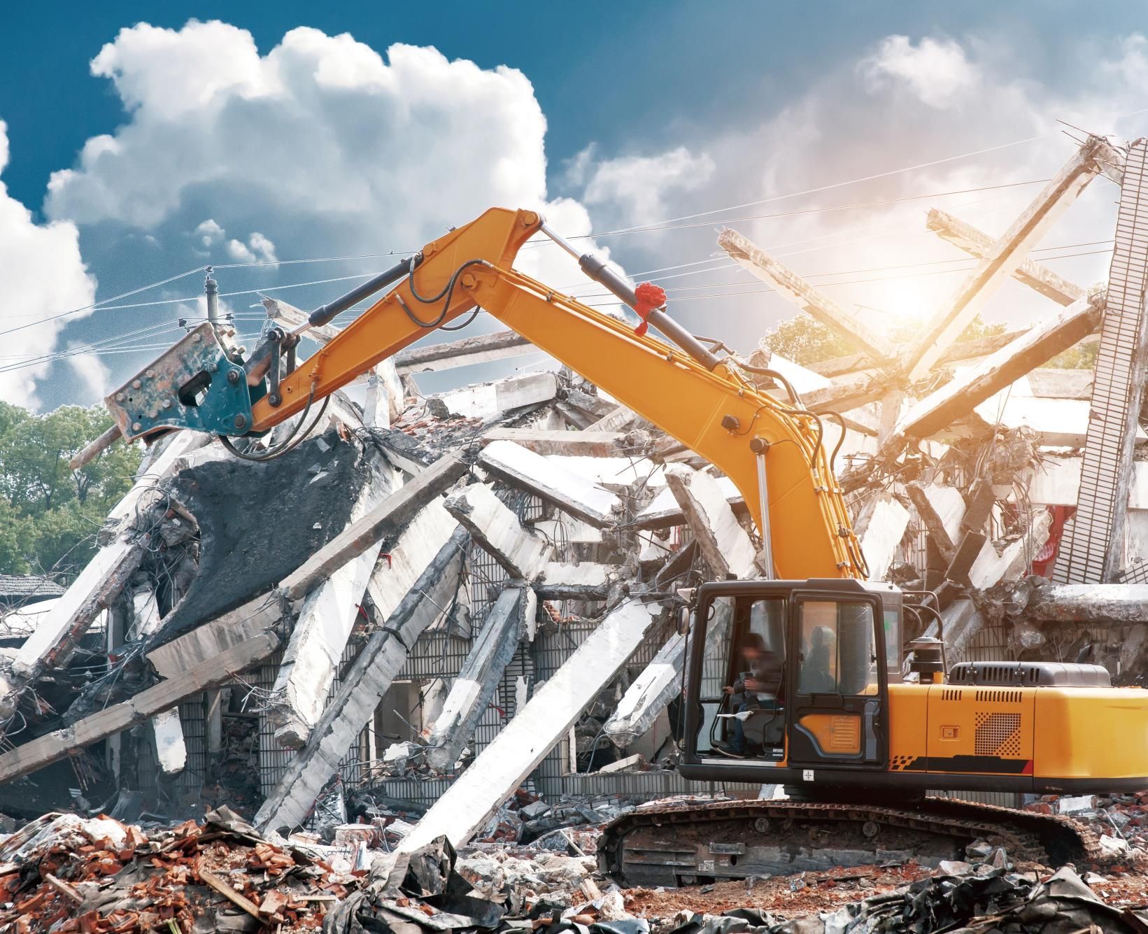 a large yellow excavator is demolishing a building