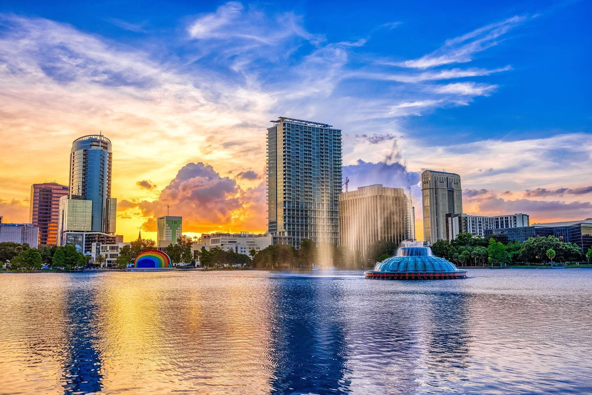 a fountain in the middle of a lake with buildings in the background