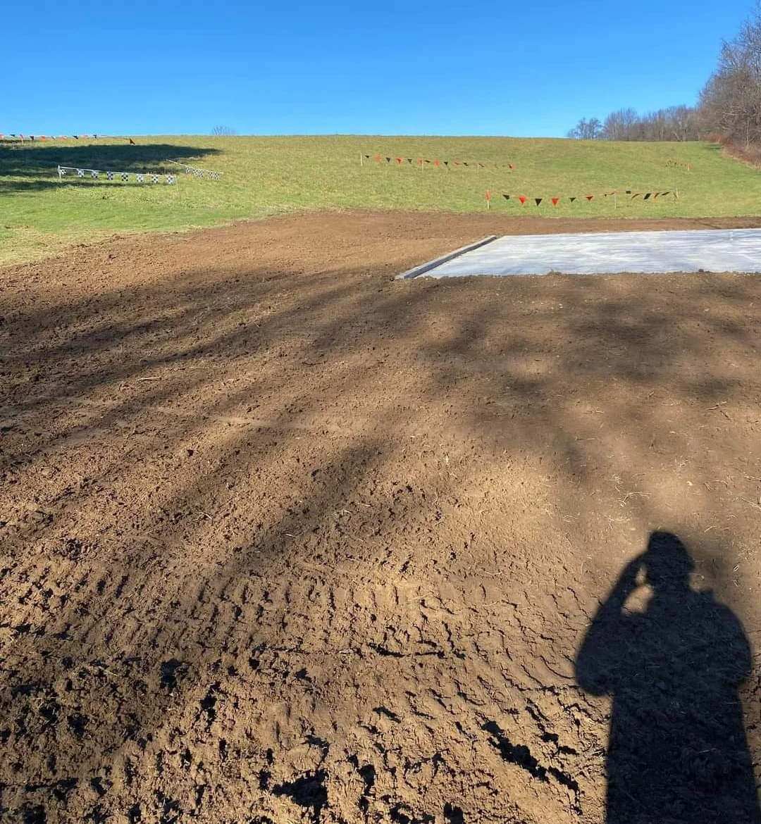 A man is surveying the grading site. Surveying is an essential part of preparing for any construction site.